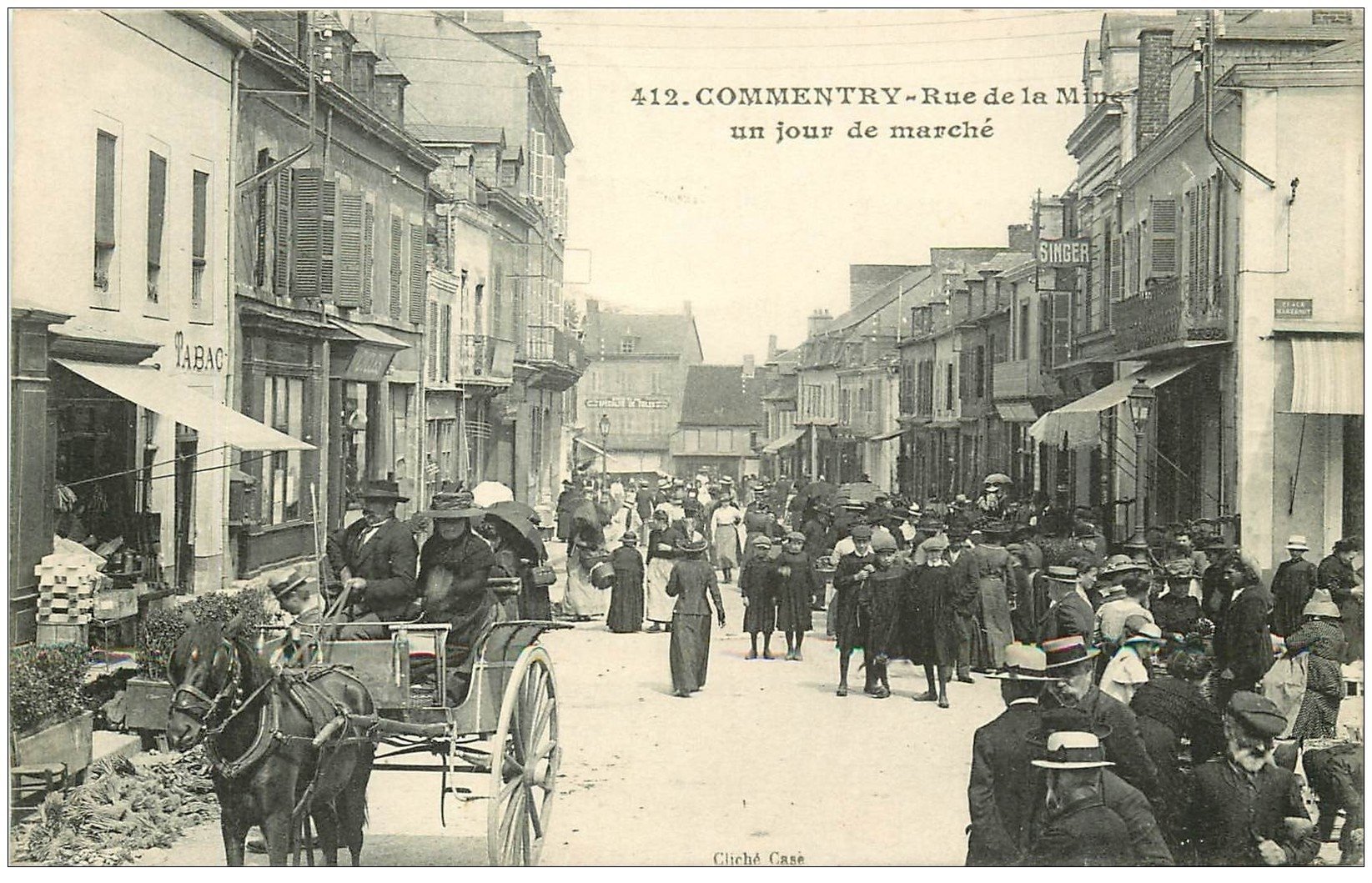 carte postale ancienne 03 COMMENTRY. Jour de Marché Rue de la Mine. Magasin SINGER et Tabac 1915